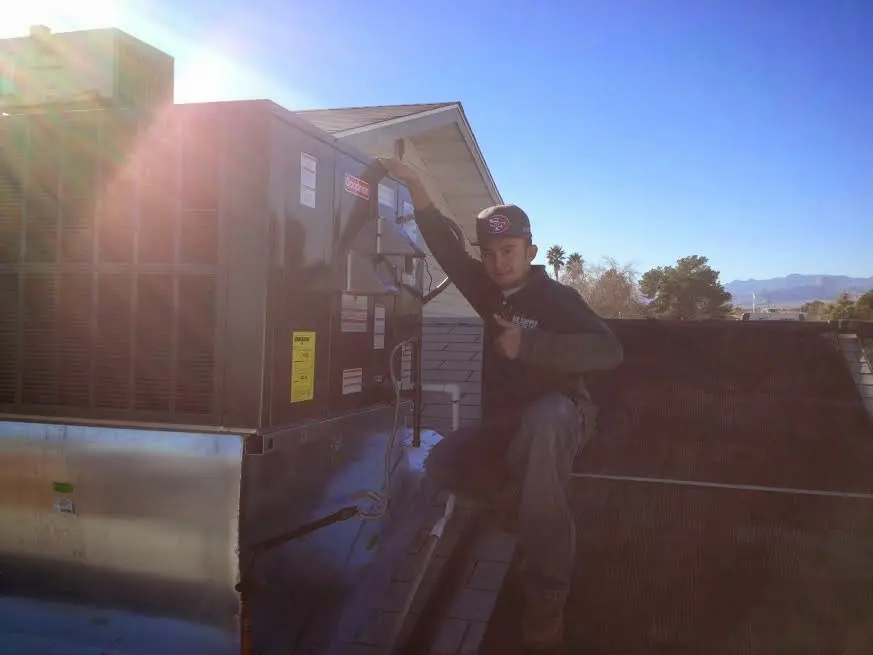 HVAC technician performing AC Tune-Up on a rooftop unit in Magna